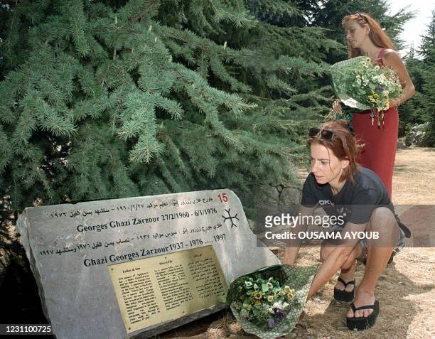 Two Lebanese women put flowers 31 August 1999 on their relative's tombstone at the Cedar of the Martyr war memorial, hidden away in the mountains in...