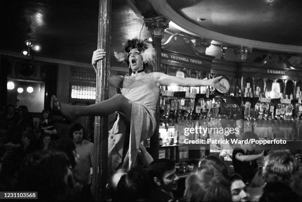 Drag artist performing with a pole at a pub in Vauxhall, South London, England, circa 1977. This image is from a series of social documentary...