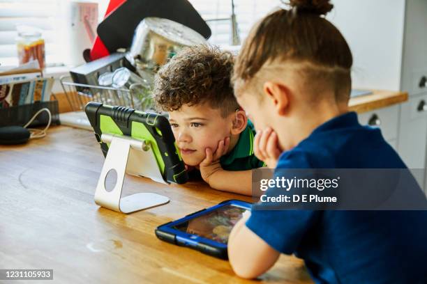 two boys on tablets in kitchen - assistive technology stock pictures, royalty-free photos & images