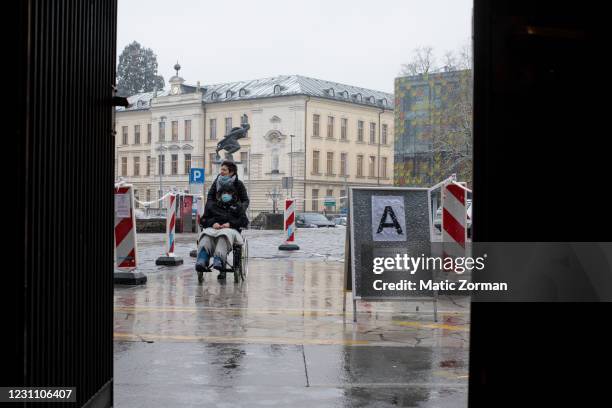 Caretaker escorts an older person on a wheelchair to the vaccination centre reserved for elderly people on February 11, 2021 in Kranj, Slovenia....