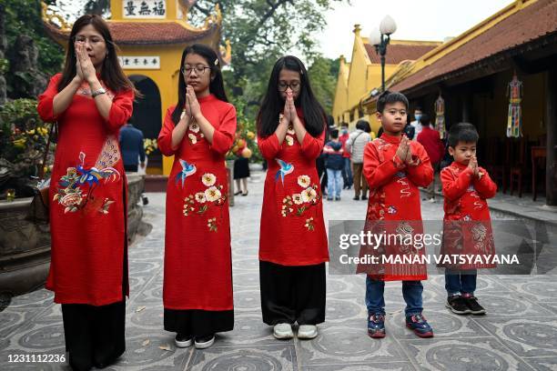 Vietnamese family dressed in traditional Ao Dai dress pray at the Tran Quoc Pagoda, one of the oldest pagodas in Hanoi on February 12, 2021 on the...