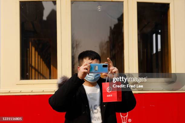 Man uses his mobile phone to take a picture of Qianmen Street ahead of Chinese New Year, the Year of the Ox, on February 12, 2021 in Beijing, China.