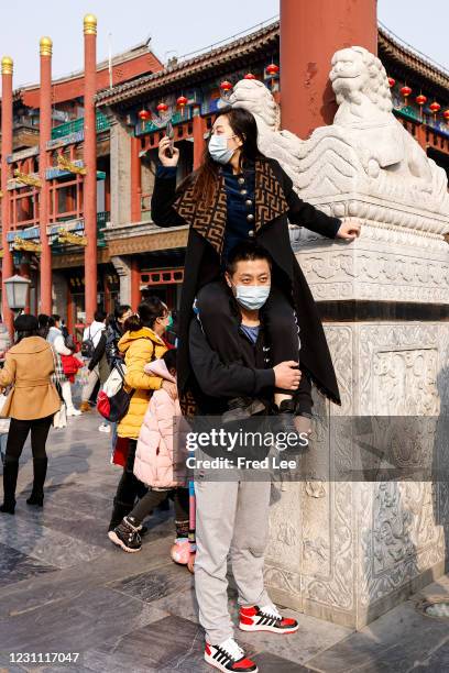 Women uses her mobile phone to take a picture of Qianmen Street ahead of Chinese New Year, the Year of the Ox, on February 12, 2021 in Beijing, China.