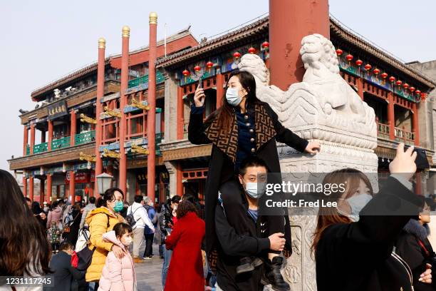 Women uses her mobile phone to take a picture of Qianmen Street ahead of Chinese New Year, the Year of the Ox, on February 12, 2021 in Beijing, China.