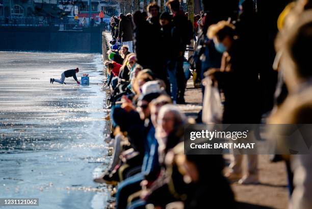 Man crawls off the icy pond as the Dutch emergency services help ice skaters off the Hofvijver pond where numerous skaters ran into problems when the...