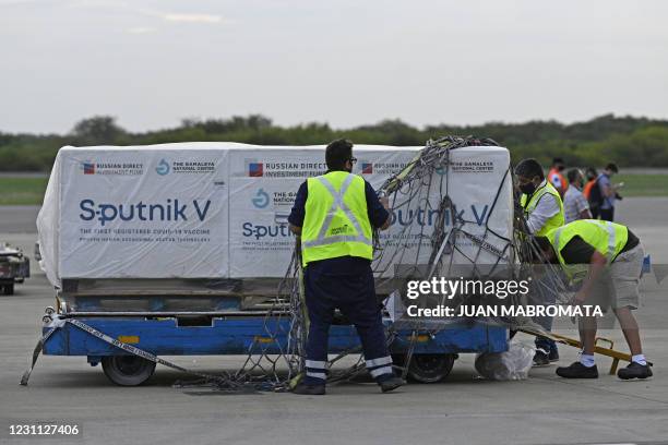 Airport workers transport shipping containers with Sputnik V vaccine doses against COVID-19, at the Ezeiza International Airport in Buenos Aires, on...