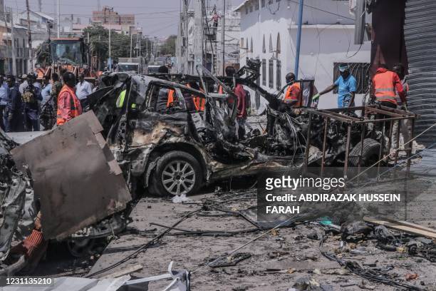 Rescue personnel and bystanders gather near debris at the site of a suicide car bombing attack near a security checkpoint in Mogadishu on February...