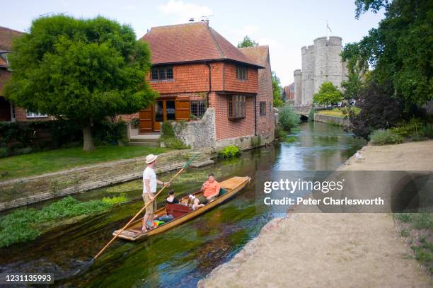 Family enjoys punting on the Great Stour river next to Westgate Gardens where people are enjoying a sunny summer's day. In the background is the...