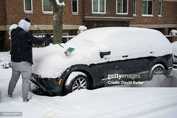 Person clears snow from a vehicle on February 13, 2021 in Seattle, Washington. A large winter storm dropped heavy snow across the region.