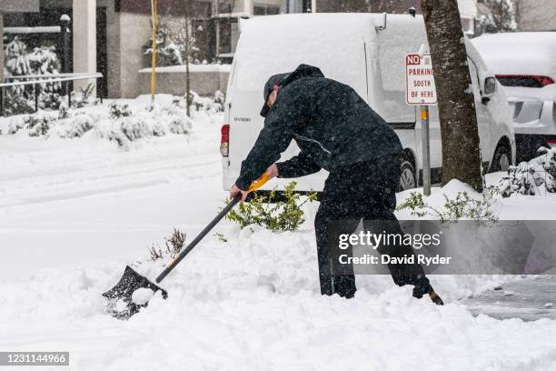 Person shovels snow outside of a business on February 13, 2021 in Seattle, Washington. A large winter storm dropped heavy snow across the region.