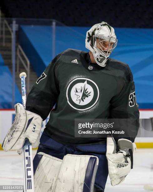 Goaltender Connor Hellebuyck of the Winnipeg Jets takes part in the pre-game warm up wearing a special military themed jersey for Canadian Armed...