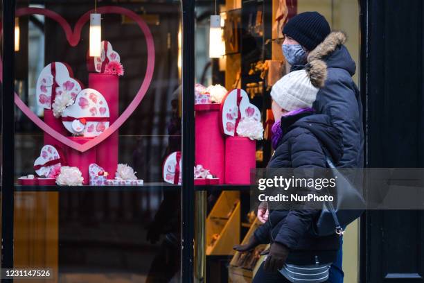 People wearing face masks walk by Butlers Chocolates shop with Valentine's Day decorations in the window, seen on Grafton Street, Dublin city center,...
