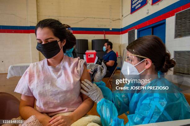 Angelica Romero is inoculated with the Moderna Vaccine for Covid-19 by a pharmacy student at Central Falls High School in Central Falls, Rhode...
