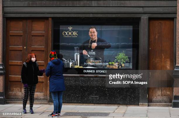Two women chatting outside a closed Dunnes Stores with an image of the celebrity, chef Neven Mcguire, in Dublin city center, during the COVID-19...