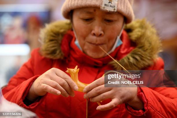 Vendor makes animal-shaped sweets at the Wangfujing shopping street in Beijing on February 14, 2021.