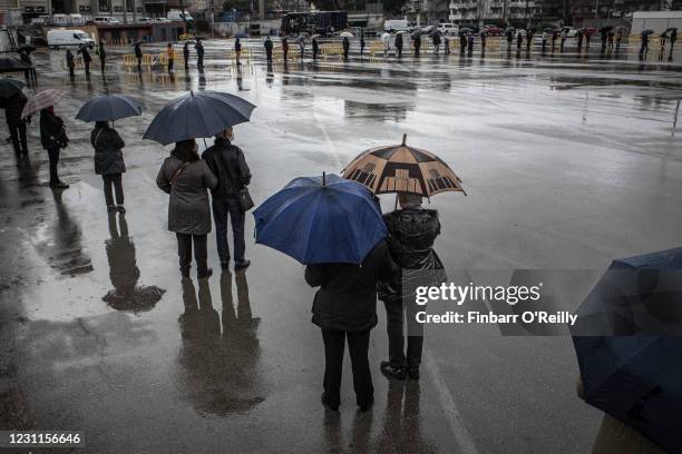Voters line up in the rain to cast their ballots for regional Catalan elections outside the Barcelona football stadium, Camp Nou, on February 14,...
