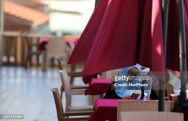Palestinian girl sits inside a coffee shop next to a beach on Valentine's day in Gaza City on February 14, 2021. Valentine's Day is increasingly...