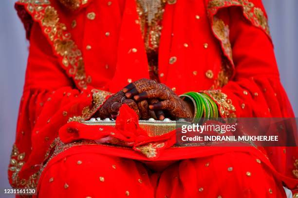 Muslim bride with her hands decorated sits on a stage during a mass marriage event in Mumbai on February 14, 2021.