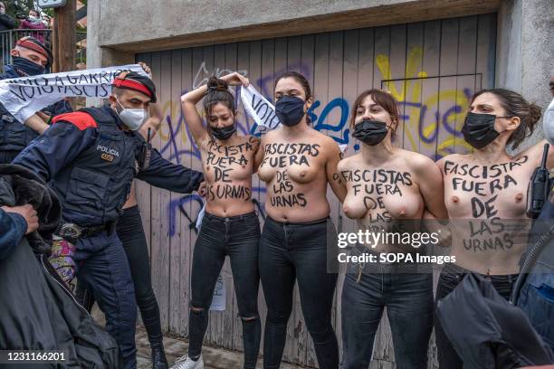 Police officers from the Mossos d'esquadra are seen arresting Femen activists with their bare breasts at the door of the Salle Bonanova electoral...