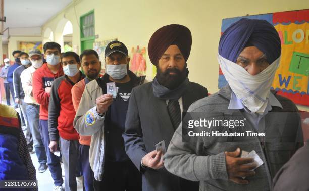 Voters show their identity cards while queuing during Punjab Municipal Election at Phase 11, on February 14, 2021 in Mohali, India. Polling is...