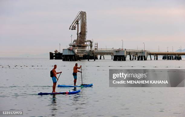 Men row on standup paddle boards in the Red Sea waters near the Eilat-Ashkelon Pipeline Company's oil terminal by Israel's southern port city of...