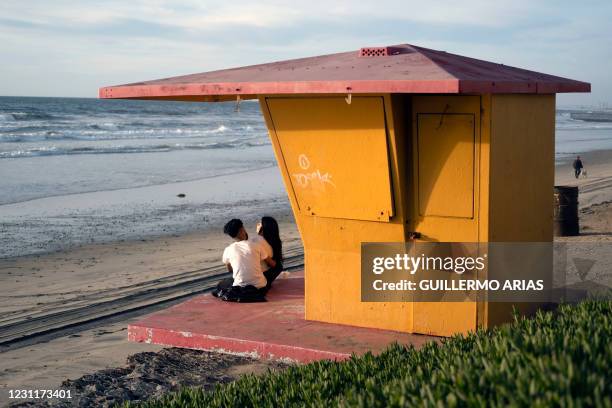 Couple sits on a closed lifeguard tower in Playas de Tijuana, Baja California State, Mexico, on Valentine's Day, on February 14, 2021. - Despite the...