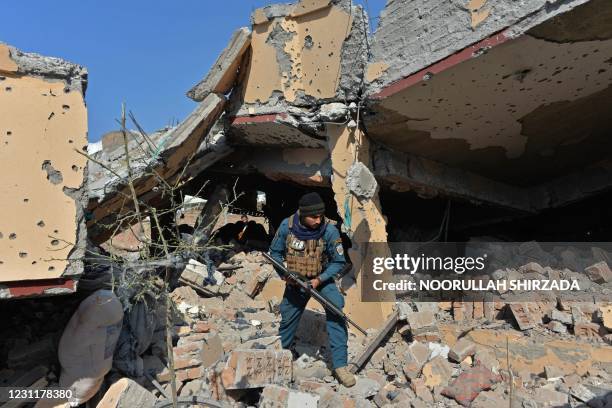 An Afghan security personnel inspects a residential house that was damaged in a gunbattle between security forces and Islamic State group fighters in...