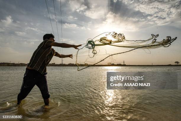 Fisherman casts his net into the Euphrates river in Iraq's southern city of Nasiriyah in the province of Dhi Qar on February 15, 2021.