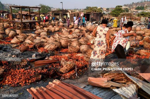 People walk past dozens of baskets full of tomatoes vandalised during deadly ethnic clashes between the northern Fulani and southern Yoruba traders...