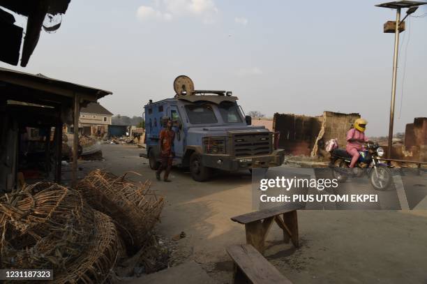 Man drives his motocycle past police armoured personnel carrier parked at the scene of violent attacks after deadly ethnic clashes between the...