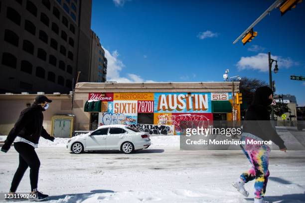 Pedestrians walk on along a snow-covered street on February 15, 2021 in Austin, Texas. Winter storm Uri has brought historic cold weather to Texas,...