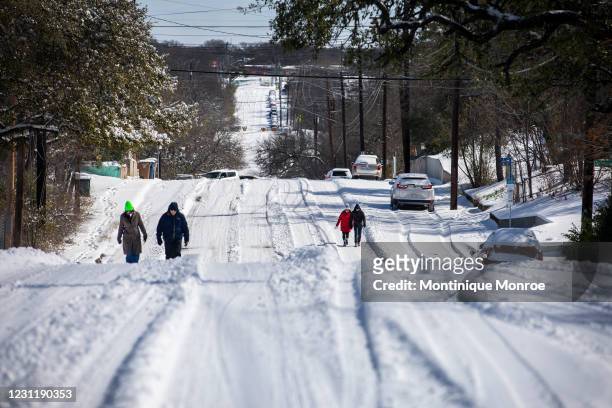 Pedestrians walk on an icy road on February 15, 2021 in East Austin, Texas. Winter storm Uri has brought historic cold weather to Texas, causing...