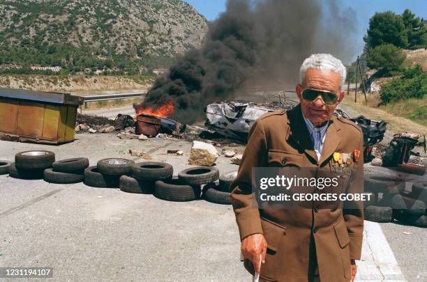 Un vieil Harki portant l'uniforme français avec ses décorations, se tient devant une barricade érigée par des enfants de Harkis, le 25 juin 1991 sur...