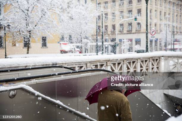 February 2021, Greece, Athen: A man enters a downtown subway during a snowstorm holding an umbrella. Photo: Socrates Baltagiannis/
