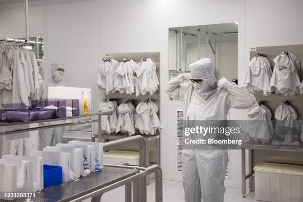 An employee dresses in protective clothing before entering the clean room at the Globalfoundries semiconductor fabrication plant in Dresden, Germany,...