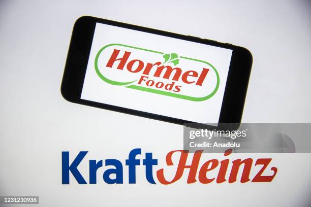 In this photo illustration, a computer screen displays the logo of "Kraft Heinz Company" and a mobile phone screen displays the logo of "Hormel Foods...