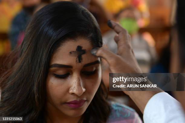 Priest marks the symbol of the cross with ash on the forehead of a Catholic Christian devotee during an Ash Wednesday service at the St.Teresa's...