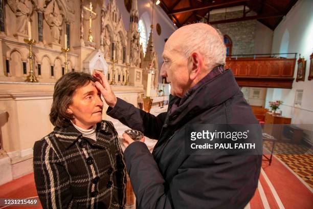 Father Brian Brady, adminsters ashes onto the forehead of Church Sacristan Breege McEleney for Ash Wednesday at St Mary's Church in Clonmany, County...