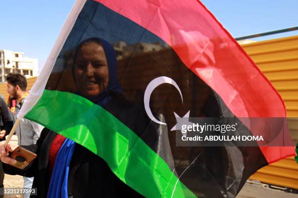Woman waves a national flag as Libyans mark the 10th anniversary of the 2011 revolution, in the eastern city of Benghazi, on February 17, 2021. The...