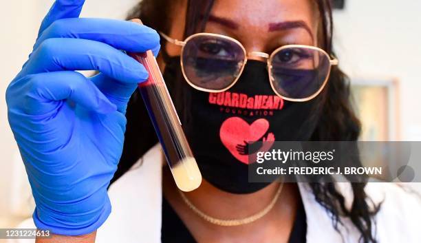 Phlebotomist Ebonie Bennett displays a vial of blood drawn during a no-cost Covid-19 antibody testing organized by the GuardHeart Foundation and the...