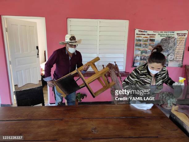 Carlos Millo, owner of a lodging for tourists, helps his wife to clean their house in Vinales, Cuba, on January 29, 2021. - At the foot of the...
