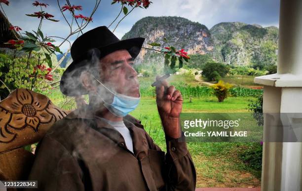 Eduardo Hernandez, owner of a private restaurant and a tobacco cultivator, smokes a cigar in his house in Vinales, Cuba, on January 28, 2021. - At...