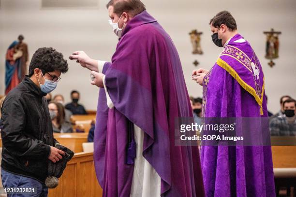 Father Mark Moore applies ashes on a kids' head during the mass at Christ the King University Parish in Athens. Father Mark Moore of Christ the King...