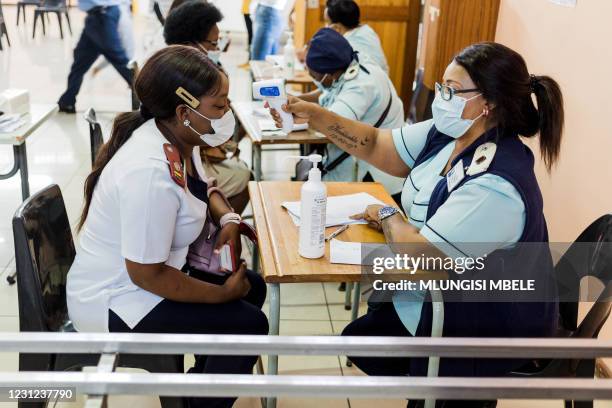 Nurse gets a temperature check before receiving a dose of the Johnson & Johnson vaccine against the COVID-19 coronavirus as South Africa proceeds...