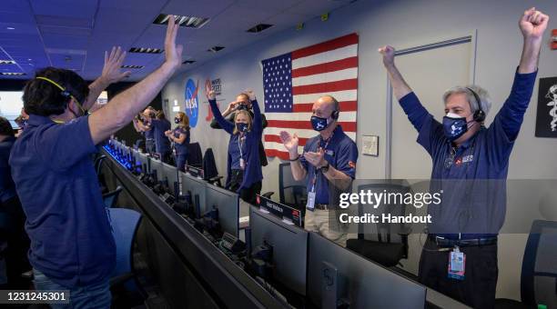 In this handout image provided by NASA, members of NASA's Perseverance rover team react in mission control after receiving confirmation the...