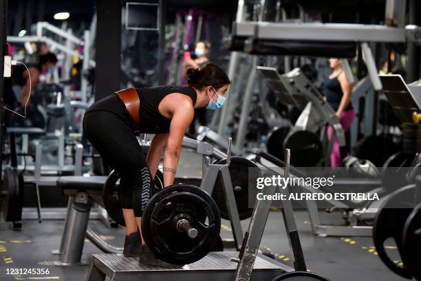 Woman exercises using a face mask to prevent contagion from COVID-19 as gyms reopen in Mexico City on February 18, 2021.