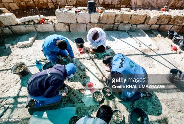 Workers employed by a pilot project run by the UN cultural agency UNESCO, restore a mosaic floor at an ancient church complex, in the small town of...