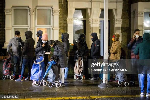 International students queue to collect food packages at the Newham Community Project food bank in east London on February 16, 2021. - "It's hard to...