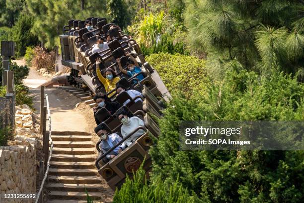Visitors seen wearing facemasks while riding on the Big Grizzly Mountain Runaway Mine Cars roller coaster during the reopening of the Hong Kong...