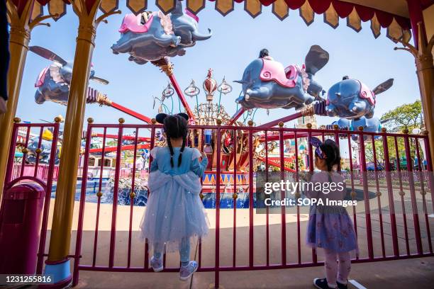 Two young girls line up for the ride of Dumbo the Flying Elephant while maintaining social distance during the reopening of the Hong Kong Disneyland...